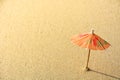 Small orange cocktail paper umbrella on the beach sand with the sunlight on the evening Royalty Free Stock Photo