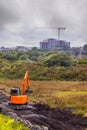 Small orange color mini digger working in a field with a wide bucket. Heavy machinery equipment. Construction industry