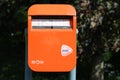 Small orange colored mailbox of PostNl at the countryside in the Netherlands