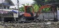 Small orange excavator or backhoe and big truck contain soil working in house construction site. dirty working