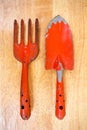 Small orange gardening shovel and fork on wooden board background Royalty Free Stock Photo