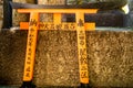 Small orange torii gate with prayers in japanese left by the worshipper by the trail in famous Fushimi Inari-Taisha Shinto Shrine.