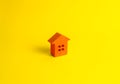 A small orange wooden house stands on a yellow background. The concept of buying and selling real estate, renting. Search for a ho Royalty Free Stock Photo