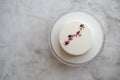 Small ousse cake with smooth white glaze decorated with dried rose buds