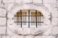 Small oval window in the pilaster on the old stone facade of the building