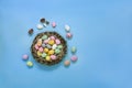 Small painted chocolate eggs in a basket nest on a blue background. Royalty Free Stock Photo