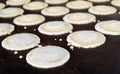 Small pancakes are baked on a hot plate. Street market