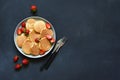 Small pancakes with berries on a plate on a concrete background.