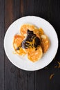 Small pancakes with chocolate glaze and candied orange on a serving plate Royalty Free Stock Photo