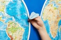 Small paper airplane on intercontinental flight to world map