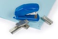 Small paper stapler and spare staples on stapled blue sheets Royalty Free Stock Photo