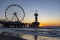 A small part of the sun is visible above the horizon and is just beyond the rear pillar of the Pier in Scheveningen with the ferri Royalty Free Stock Photo