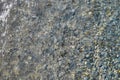 Small pebbles and wet sand on the sea beach; water line. Calm transparent water Royalty Free Stock Photo