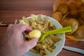 Small peeled potato is held by one hand over a bowl of potato peel