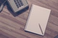 Small pencil on blank notebook with vintage dial phone Royalty Free Stock Photo