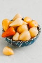 Small pickled hot peppers in a blue cup on a gray concrete background. tinted beige