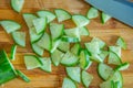 Small pieces of cucumber for salad on a wooden cutting board and cook knife Royalty Free Stock Photo