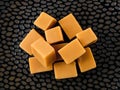 Small pile of of caramel vanilla fudge candies on a black textured ceramic plate. Fresh tasty chewy bonbons made of milk and sugar Royalty Free Stock Photo