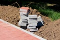 Small pile of grey and light red stone tiles next to sidewalk surrounded with dry soil and grass Royalty Free Stock Photo