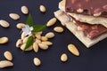 A small pile of peeled almonds and a bar of white and milk chocolate with almonds in the nut