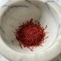 A small pile of saffron threads (Crocus sativus) sits inside a marble mortar. The Royalty Free Stock Photo