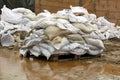 Small pile of white sandbags put on wooden pallet prepared to be put on top of temporary flood protection wall surrounded with