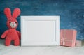 Small pink bunny sits next to gifts for children and a blank white frame for children`s day and birthday greetings.copy space.