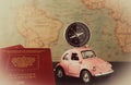 Small pink car with a compass on the roof and passports on a background of vintage maps, travel concept