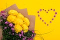 Small pink chrysanthemums in the shape of heart and large bouquet of lush flowers on yellow background with copy space. All lovers