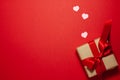 Small pink hearts near the brown paper gift box with a red ribbon bow. Valentines day concept. Flat lay