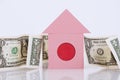 A small pink house stands on the background of American banknotes, a white background. The concept of a bank loan secured by real Royalty Free Stock Photo