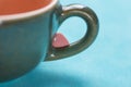 Small Pink Red Heart Shape Sugar Candy on the Handle of Coffee Tea Cup on Light Blue Background. Valentines Royalty Free Stock Photo