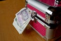 Small pink strongbox with silver edges holding thick pack of money (Czech Crowns, CZK) Royalty Free Stock Photo