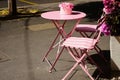 small pink terrace table with flower pot. wood and metal pink foldable patio chairs. outdoor furniture. Royalty Free Stock Photo