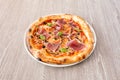 Small pizza with serrano ham, black olives, basil leaves, slices of mushroom Royalty Free Stock Photo