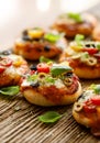 Small pizzas with the addition of cherry tomatoes, olives, mozzarella cheese and fresh basil on a rustic wooden background Royalty Free Stock Photo