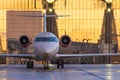 A small plane stands on the apron platform on the background of a glass terminal building with sunset light reflected in the sky Royalty Free Stock Photo