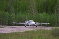 Small plane stands on the runway against the background of the forest