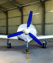 small plane with a three-bladed propeller of private aviation stands covered with a cover in a bright hangar Royalty Free Stock Photo