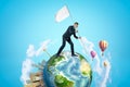 Small planet Earth with modern city popping up on one side and hot-air balloons flying in sky, and businessman walking Royalty Free Stock Photo