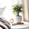 A small plant sits on a white table next to a bed. Royalty Free Stock Photo
