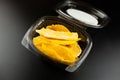 Small plastic box or casserole with slices of dried mango on black background Royalty Free Stock Photo