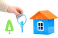 a small plastic house with a hand holding out the keys on a white insulated background. the concept of selling, buying, or Royalty Free Stock Photo