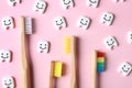 Small plastic teeth with happy faces and wooden brushes on color background