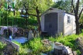 Small plastic tool storage shed placed in spring terrace garden, with round table in front