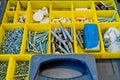 Small plastic yellow boxes with different screws and fasteners. Selective focus Royalty Free Stock Photo