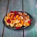 A small plate with waffles and frozen berries, red currants and sea buckthorn, poured with syrup and sprinkled with Royalty Free Stock Photo