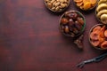 Small plates with dried fruits date palm fruits, dried apricots, figs and nuts almonds for Iftar in Ramadan on the dark red-