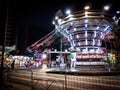 In the small playground at night, the children are racing in the rotating seats.