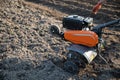 Small plowing machine in hands of a farmer making arable in black soil